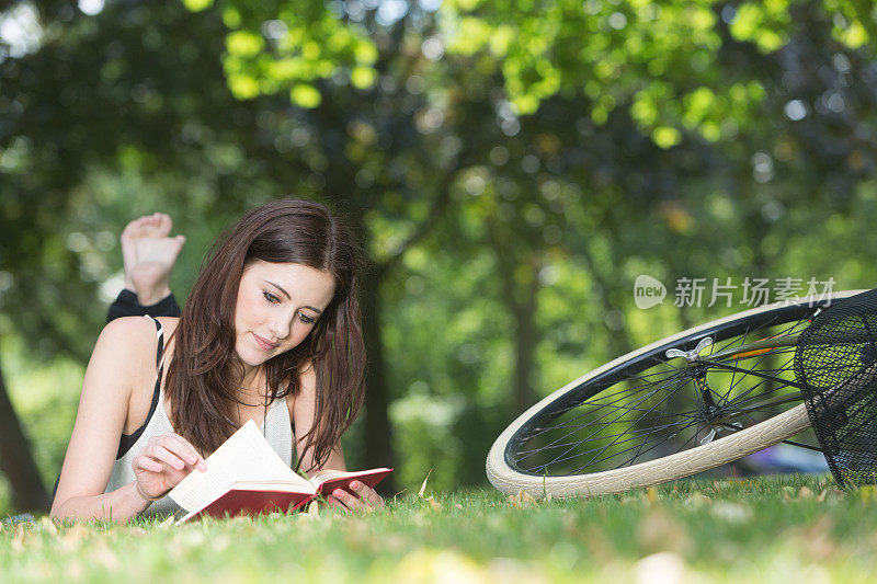 女孩在公园里她的自行车旁边看书