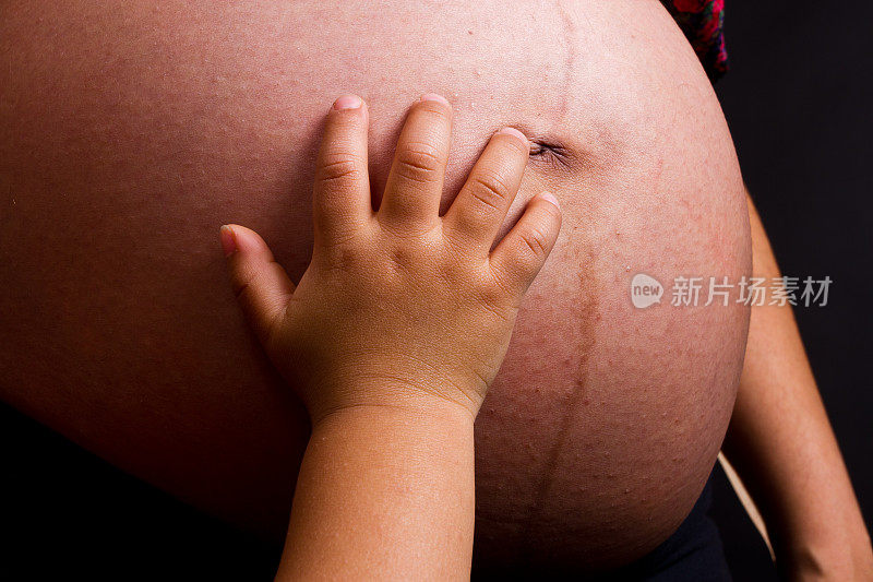 孕妇展示她的肚子上的男孩触摸它