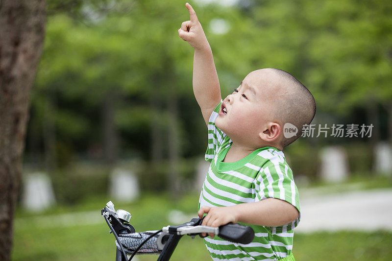 小男孩骑着自行车向上看