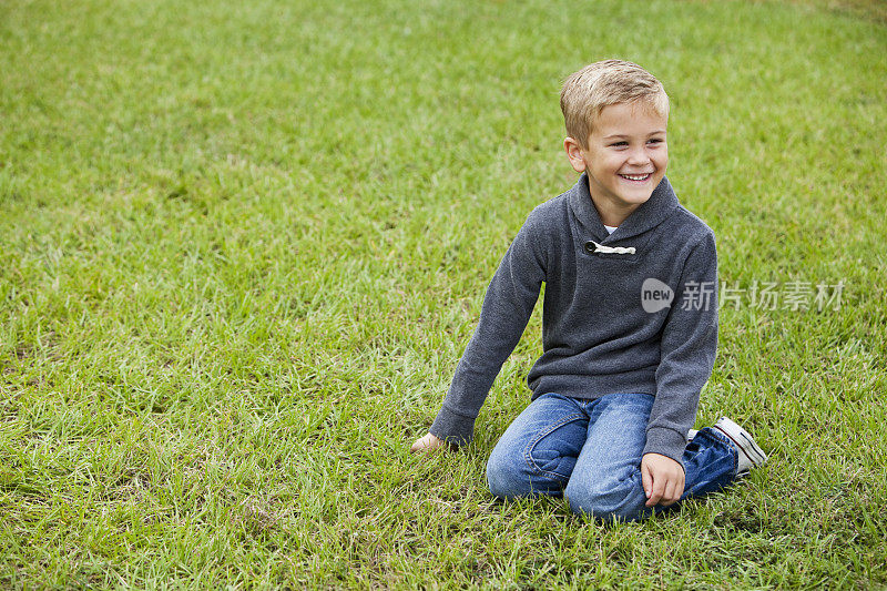 小男孩跪在草地上