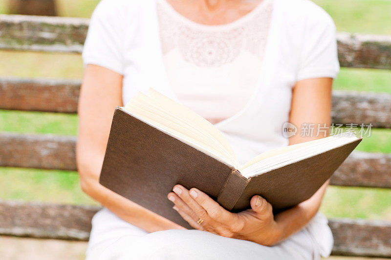 老妇人在公园长凳上看书
