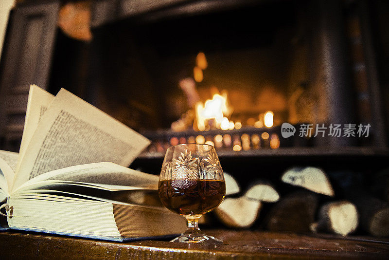 家里的壁炉，打开的书和一杯威士忌