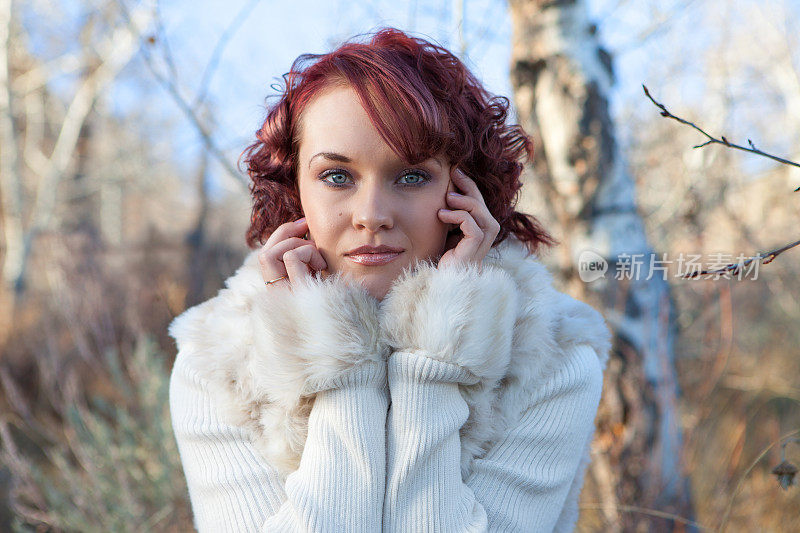 森林里穿着白色毛皮大衣的年轻女子