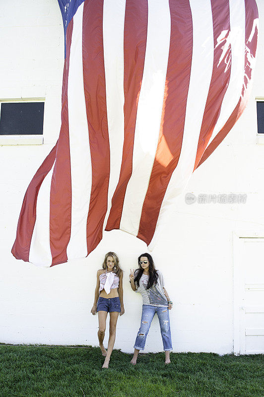 美丽的年轻女子站在一面美国国旗旁