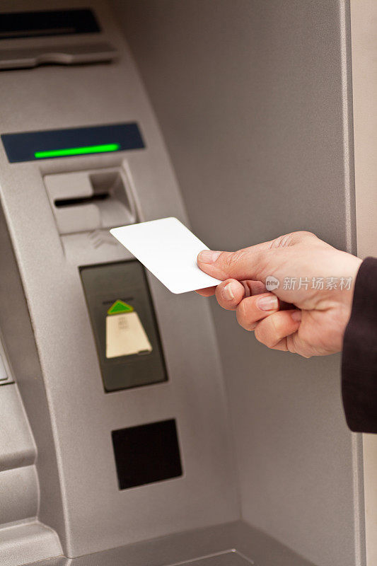 人们在自动取款机上插入信用卡