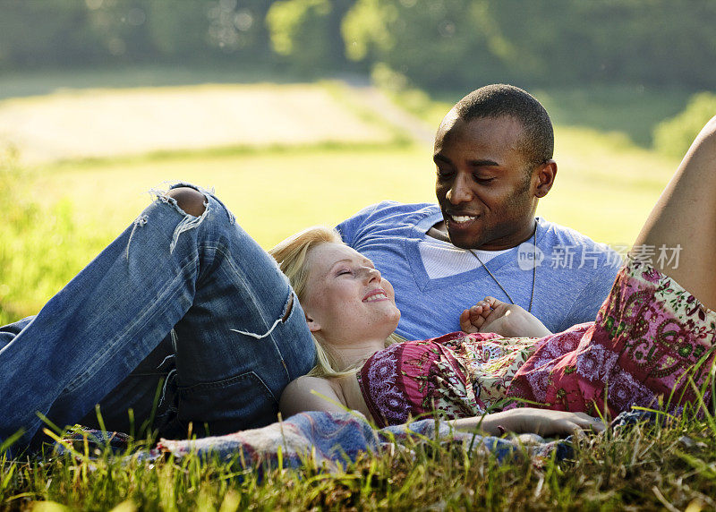 一对浪漫的年轻夫妇躺在草地上