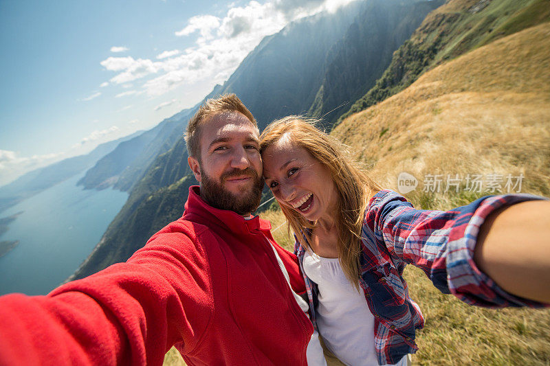 年轻夫妇在夏天徒步旅行，在山顶自拍