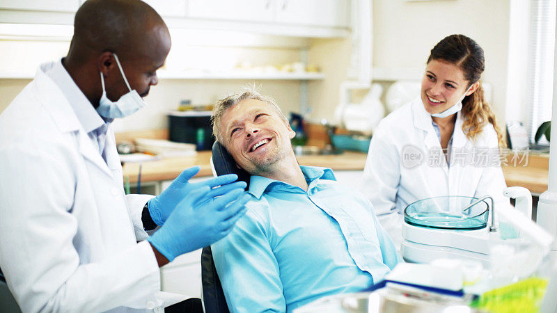 牙医与病人交谈，病人微笑着回应，助理看着