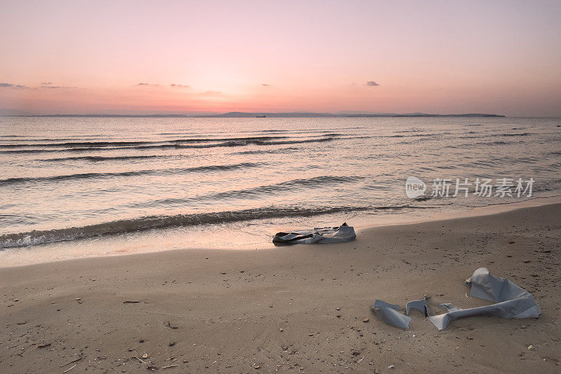 日出时希腊岛的海滩上有难民船的残骸