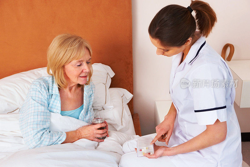 护士向一位年长的女性病人解释药物治疗