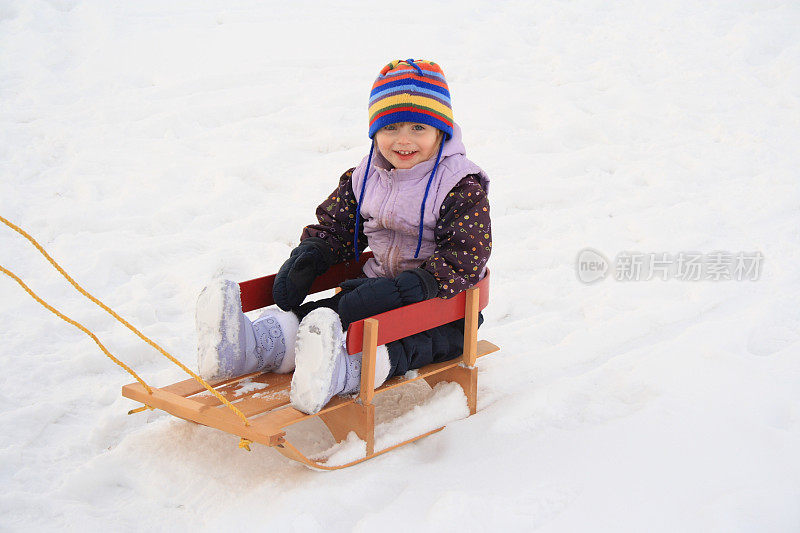 小女孩高兴地拉着雪橇