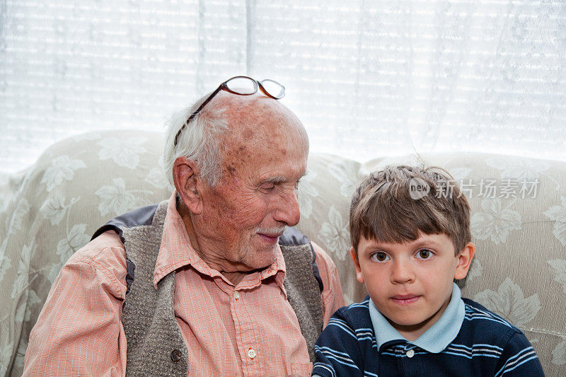 爷爷微笑着看着沙发上的孙子。