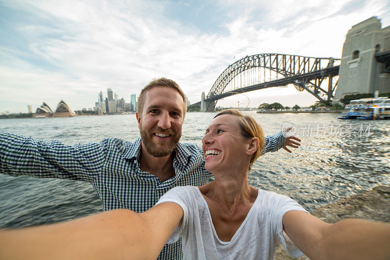 一对年轻夫妇在悉尼港拍自拍照