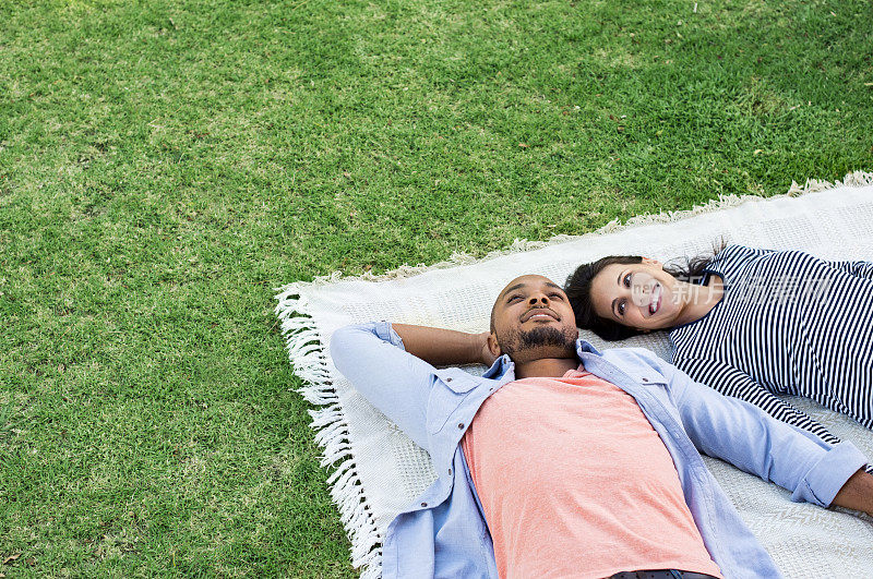 一对夫妇躺在公园的毯子上