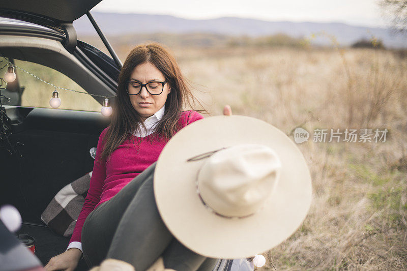 一个年轻女人坐在外面的后备箱里