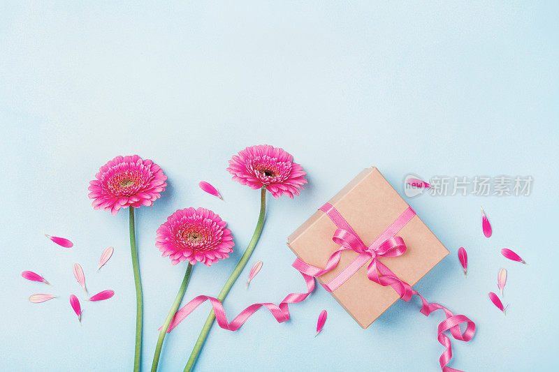生日、妇女或母亲节贺卡。春季作文用粉红色的花和礼盒在蓝色的桌子上俯视图。