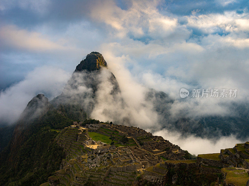 马丘比丘被从云层中射出来的第一缕阳光所照亮。印加古城是秘鲁最受欢迎的旅游目的地。雾、云和雾笼罩着山谷。
