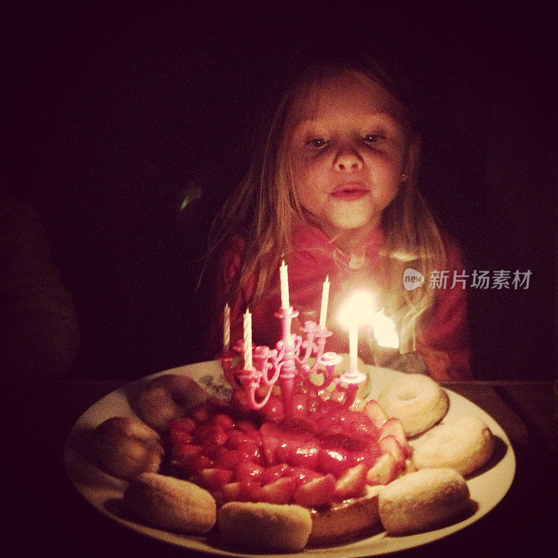 生日女孩吹灭她生日蛋糕上的五根蜡烛