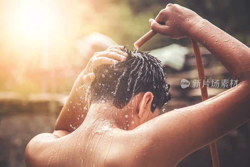 一个年轻的印度男孩在水龙头下洗澡