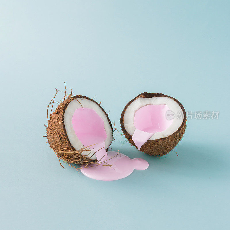 把椰子撕成两半，倒入粉色牛奶。极简主义。食品创意概念。
