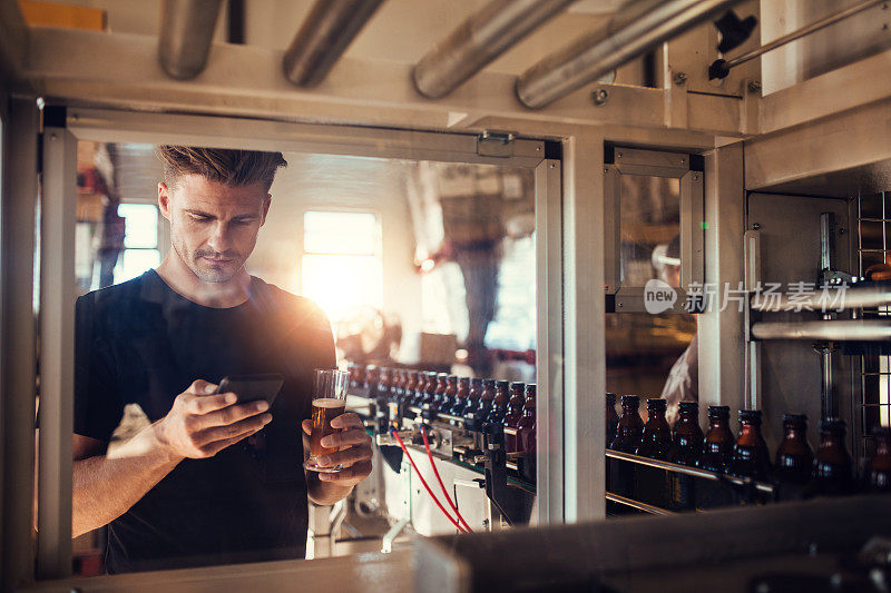 年轻人在啤酒厂使用手机