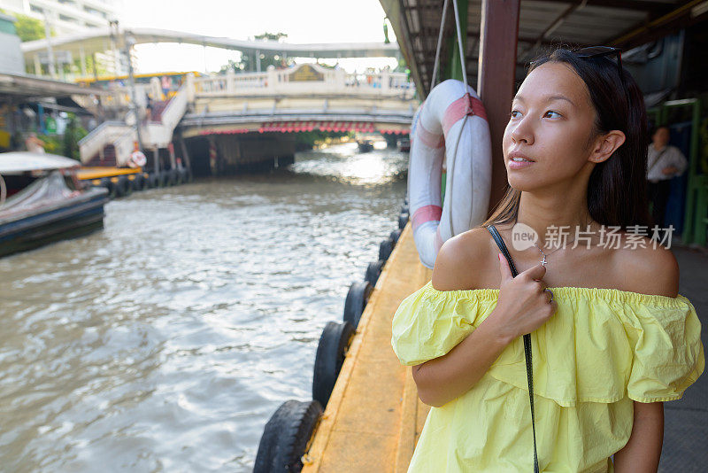 年轻美丽的多民族旅游妇女的肖像在水出租车站在泰国曼谷