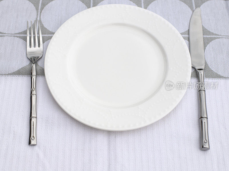亚麻桌布上的白色餐盘、刀叉