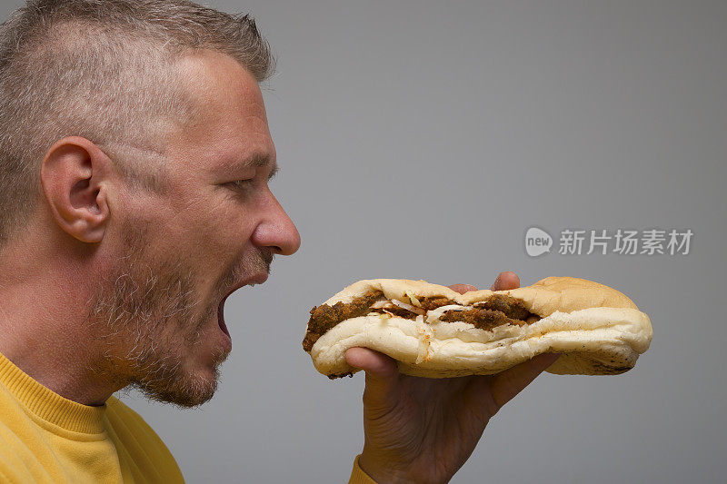 饥饿的大人捧着炸肉排中的小圆面包，准备吃