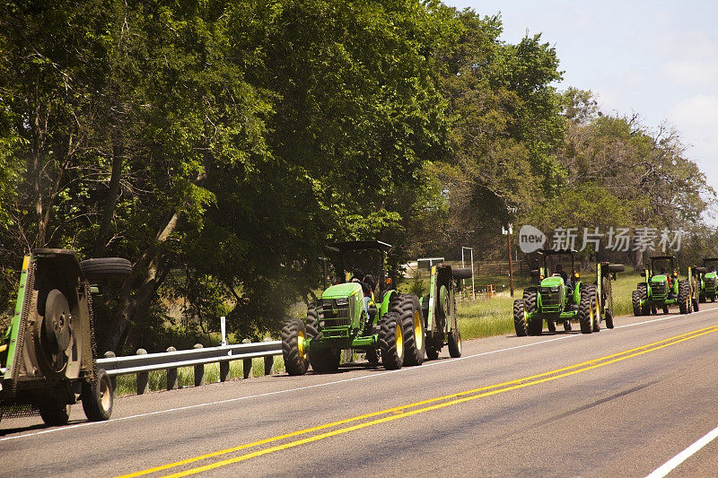 交通:约翰迪尔拖拉机在德州的路边割草。