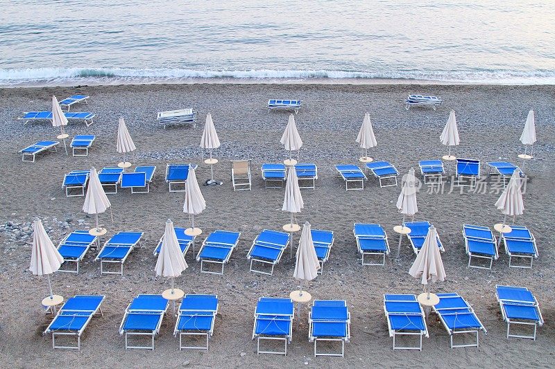 黄昏时分，意大利莱万托海滩，空荡荡的沙滩上有日光浴躺椅