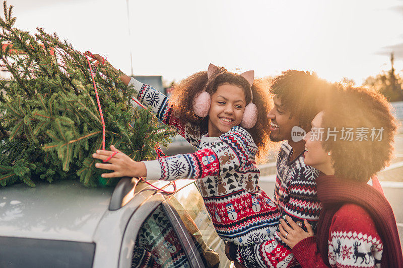 微笑的孩子把圣诞树绑在车上