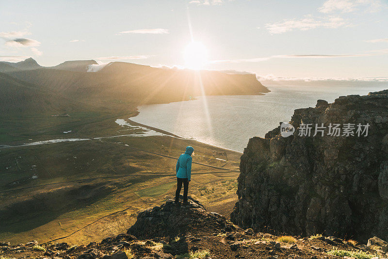 穿着蓝色雨衣的女人看着峡湾的风景