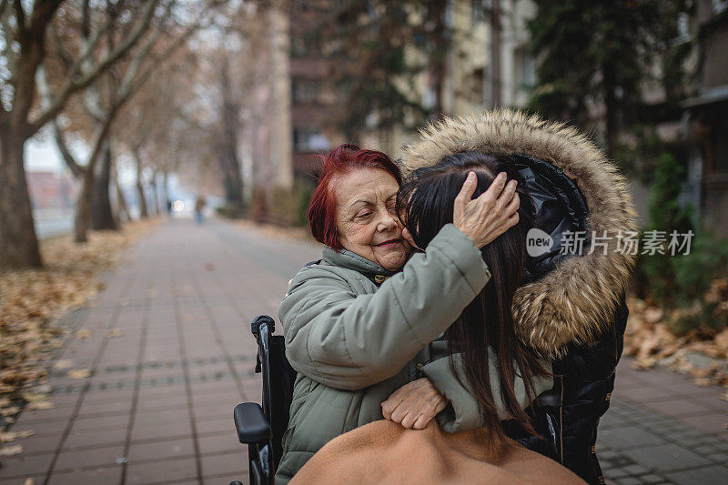 可爱的女儿在轮椅上亲吻她的母亲