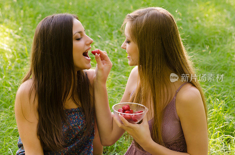 女朋友们在夏天的草地上吃草莓