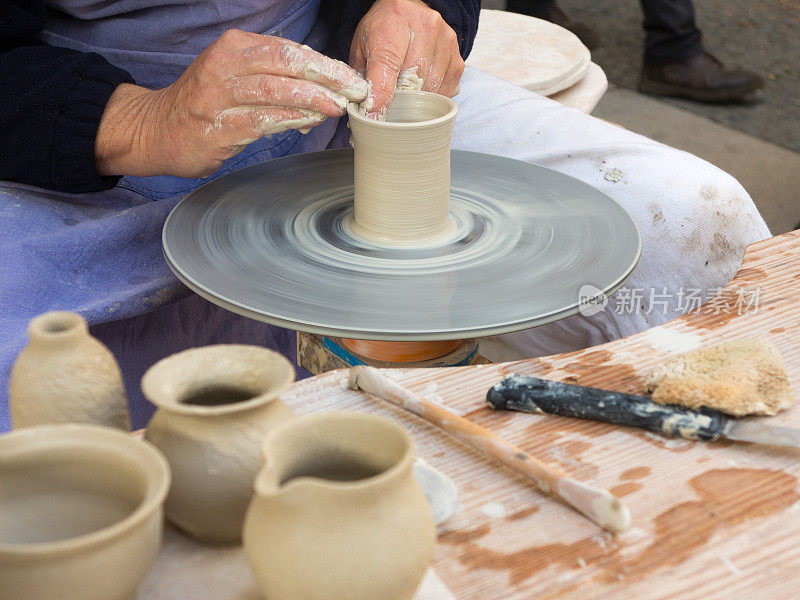 陶工的双手在陶工轮上工作，将粘土制成马克杯