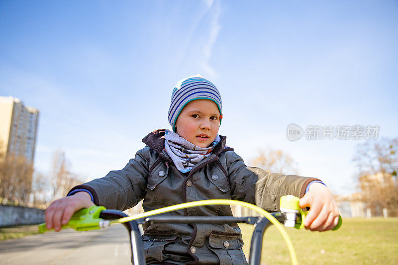 一个小男孩在户外的公园里骑自行车。一个孩子在骑一辆儿童自行车