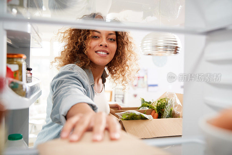 从冰箱里往外看，女人打开了在线家庭食品外卖