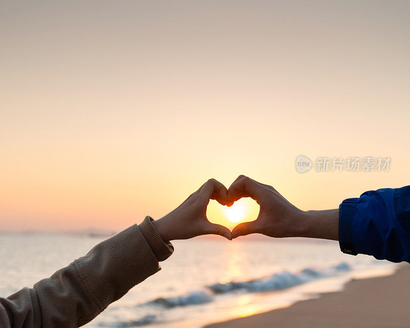 双手在沙滩上创造一颗心