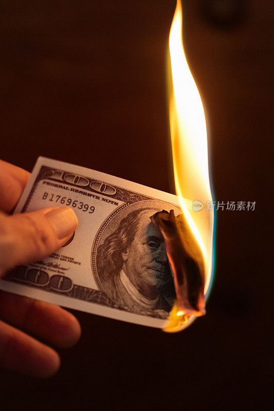 手里拿着正在燃烧的百元美钞