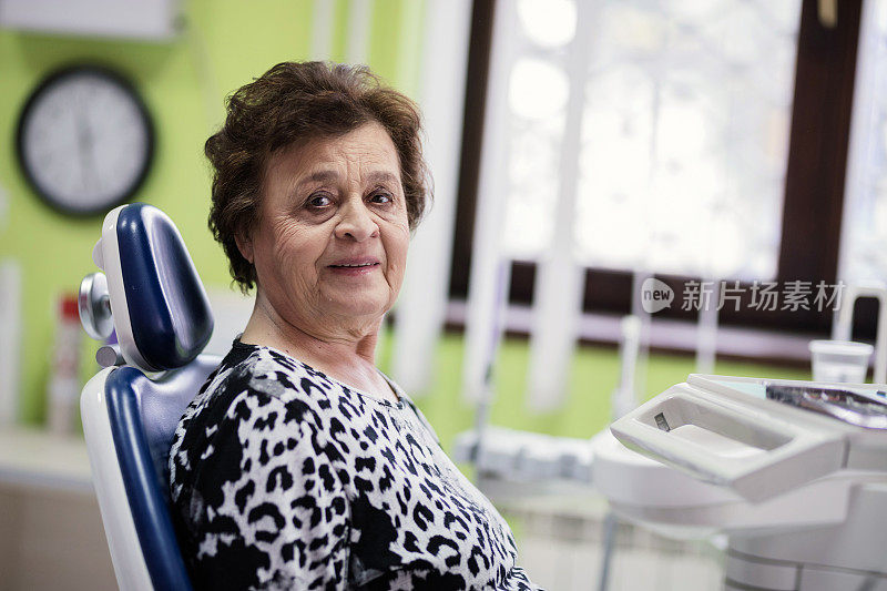 快乐的老女人坐在牙医的椅子上