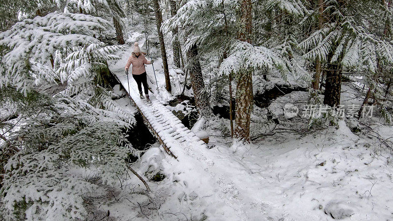 女性徒步旅行者走在被雪覆盖的木板路上