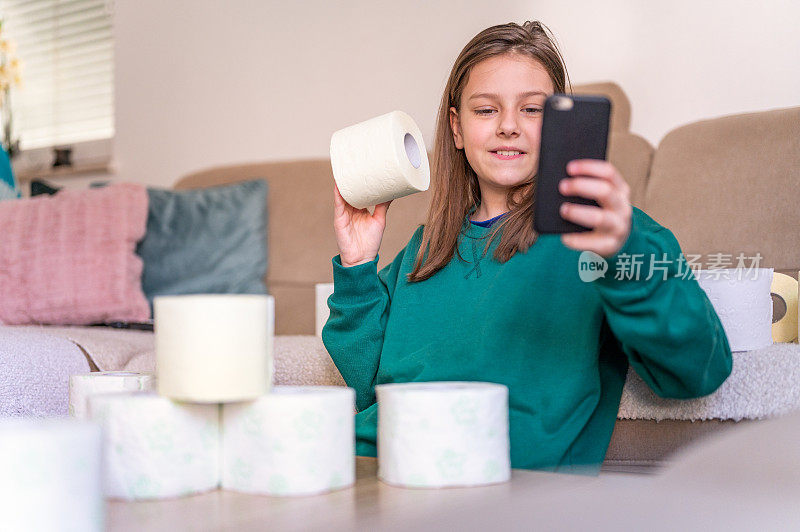 女孩在家里玩一堆卫生纸，手里拿着手机