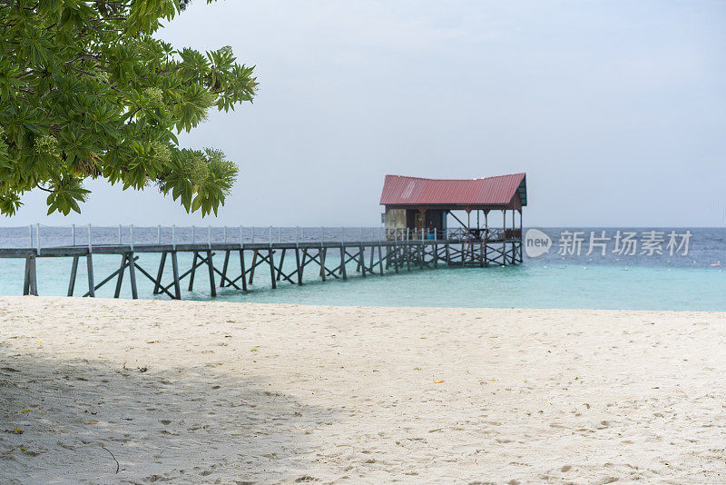 背景是在马来西亚婆罗洲的蓬蓬沙滩上，码头在海上奔跑。