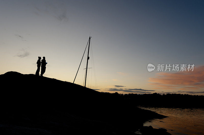 在群岛上，一对浪漫的情侣在日落时分的岩石上