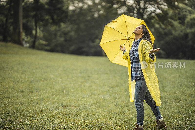 快乐的女人微笑着行走在雨天