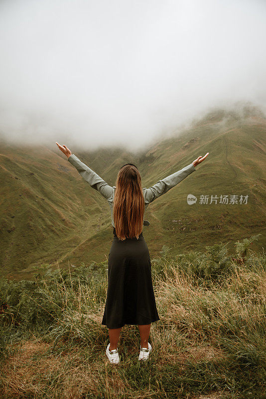 年轻的女人在迷雾中高举着双臂