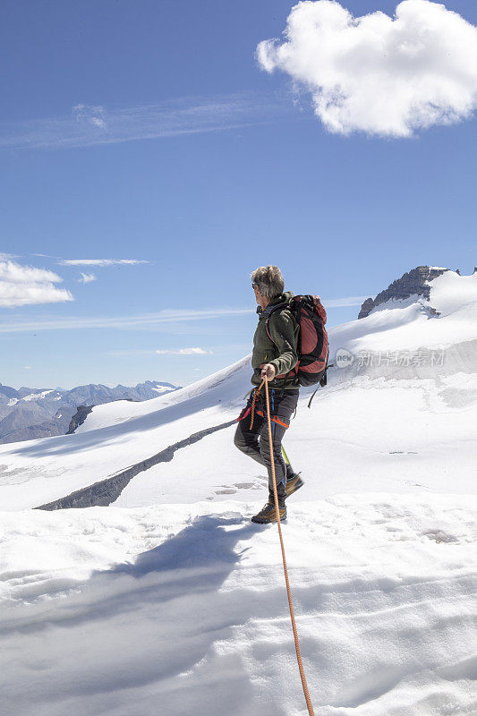 一位男性登山运动员到达了雪山的顶峰