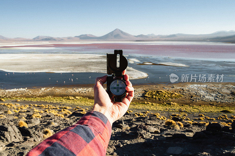 玻利维亚Altiplano，在日落时分，一名男子手持指南针站在科罗拉多州的拉古纳湖前