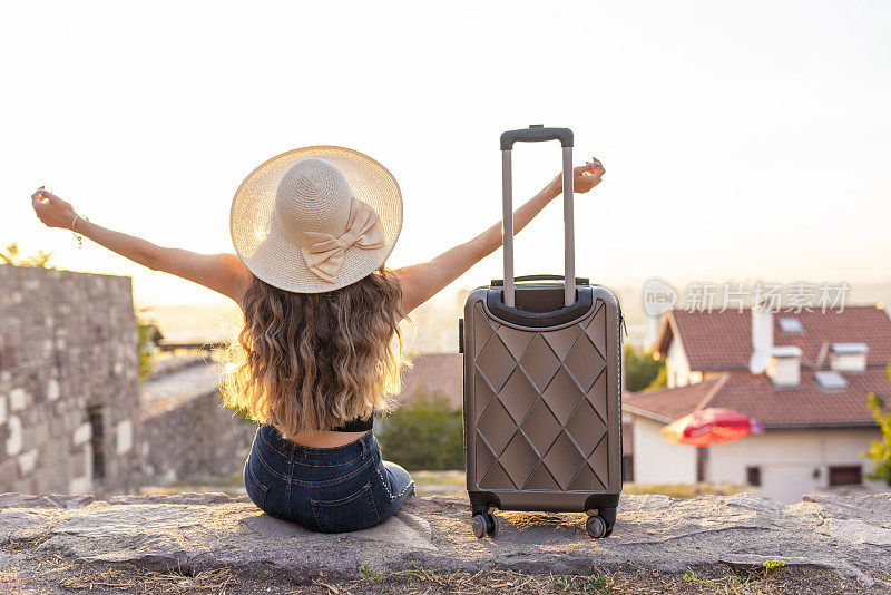 年轻的金发女人提着箱子在街上旅行