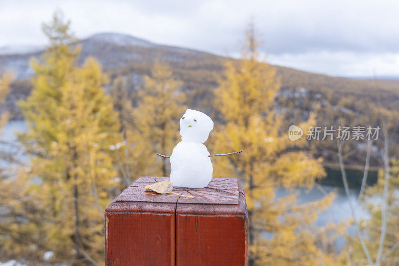 有雾有雪的秋天，湖边山上森林里的栏杆上有一个小雪人